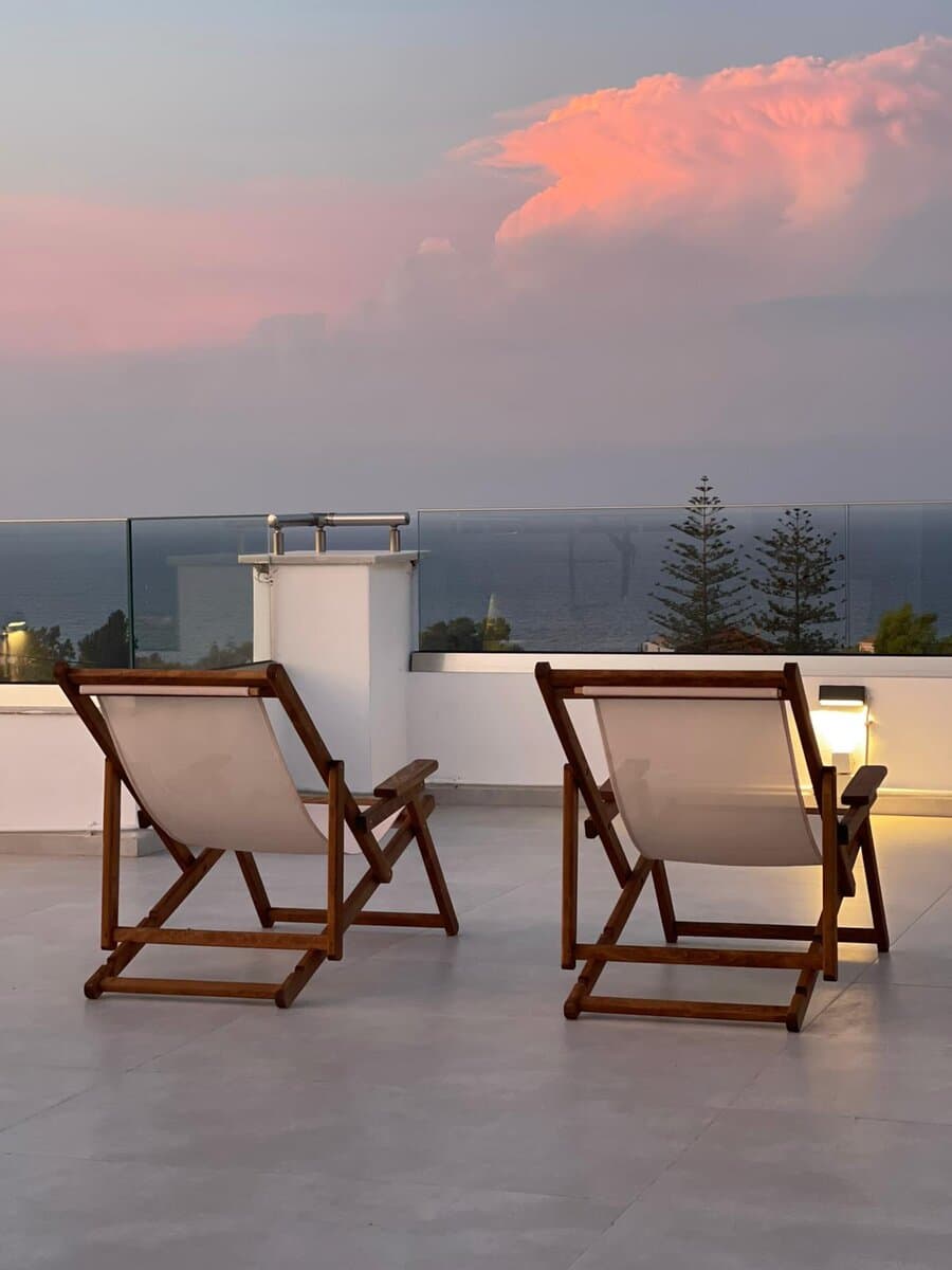 Deck chairs on the rooftop overlooking the sea at sunset