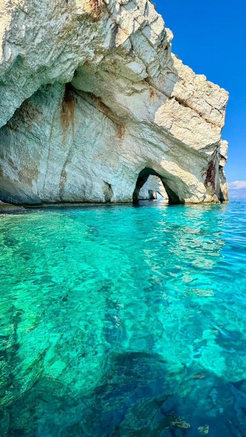 Crystal clear turquoise water beside the white limestone cliff arch
