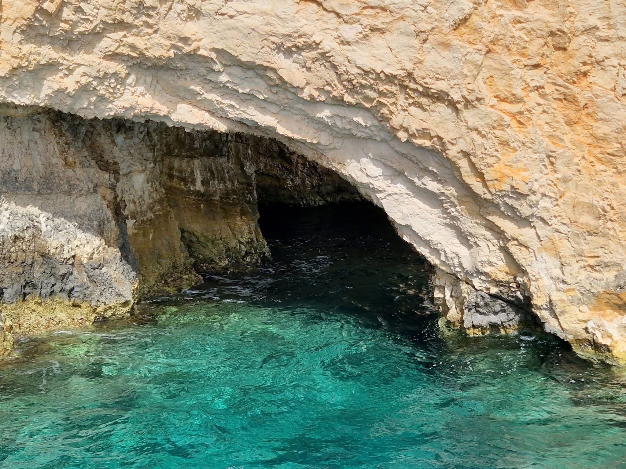 Close-up of a cave entrance revealing a turquoise water pool inside