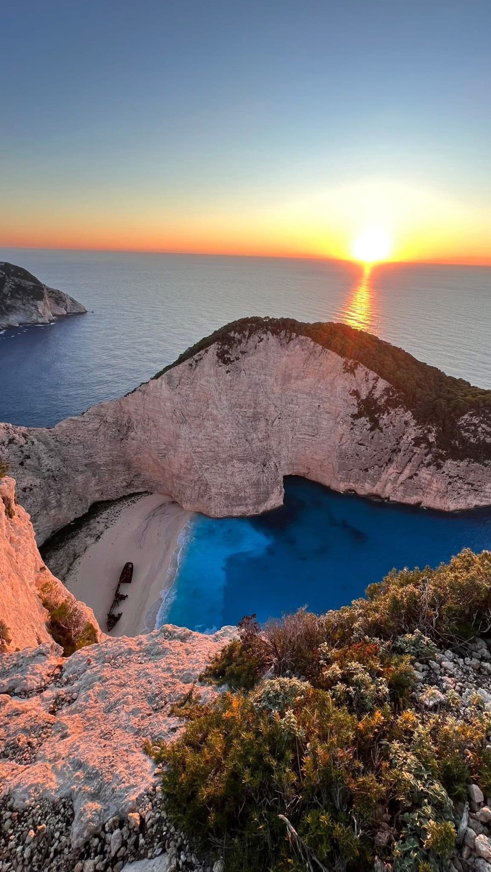 Navagio Beach at sunset with golden light over the cliffs